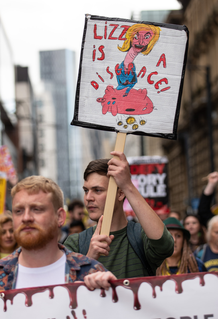 A protester holds a sign reading 'Lizz is a disgrace'
