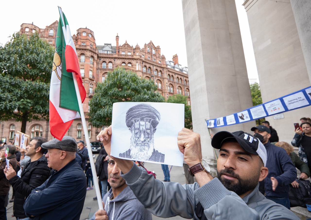 A group of male protestors hold up an Iranian flag and a bloodstained picture of Iran's supreme leader Ayatollah Ali Khamenei