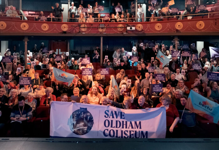 The audience at Oldham Coliseum Theatre, holding up banners and signs to save the theatre