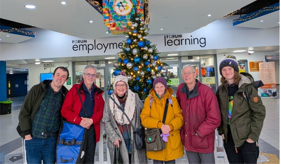 Six Green Party members standing in front of the Christmas tree in Wythenshawe Forum.